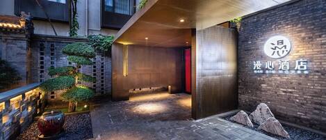 A hotel entrance with a modern design, a reception desk, and a signboard.