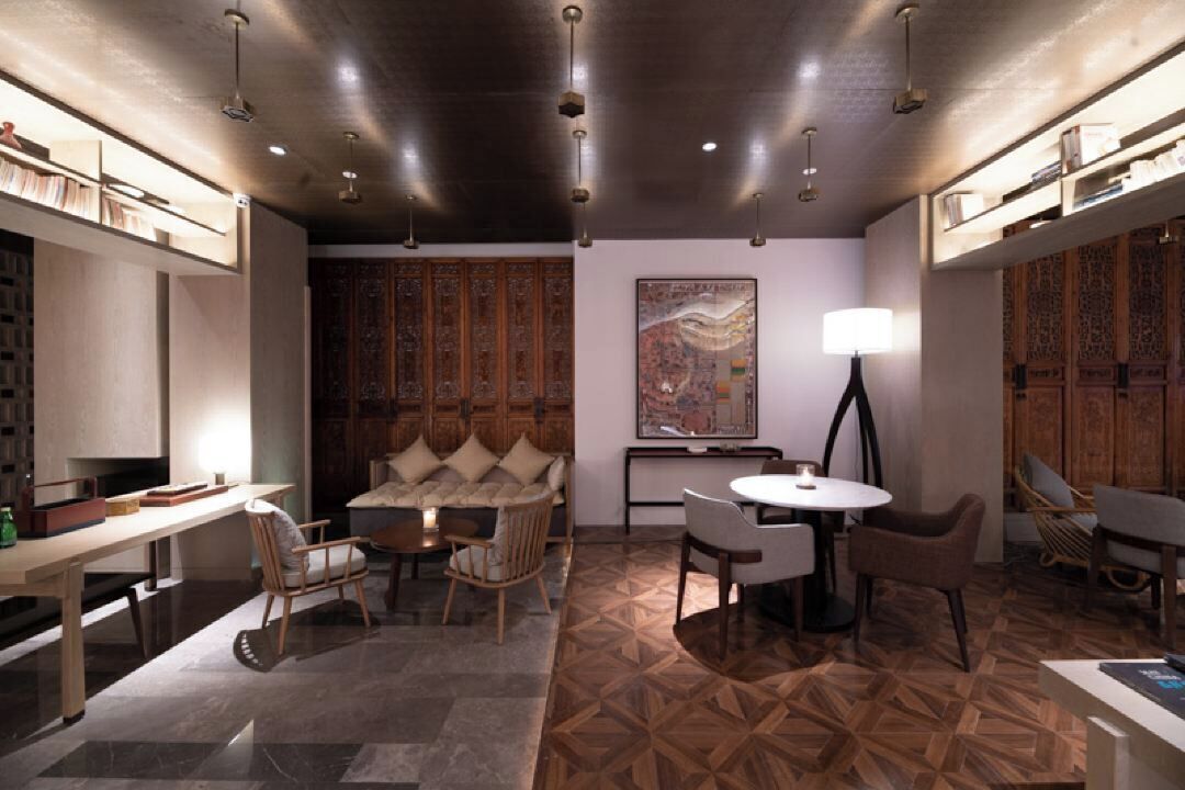 A modern interior with a dining area, a sofa, a round table, and a large abstract painting.