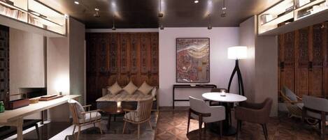 A modern interior with a dining area, a sofa, a round table, and a large abstract painting.