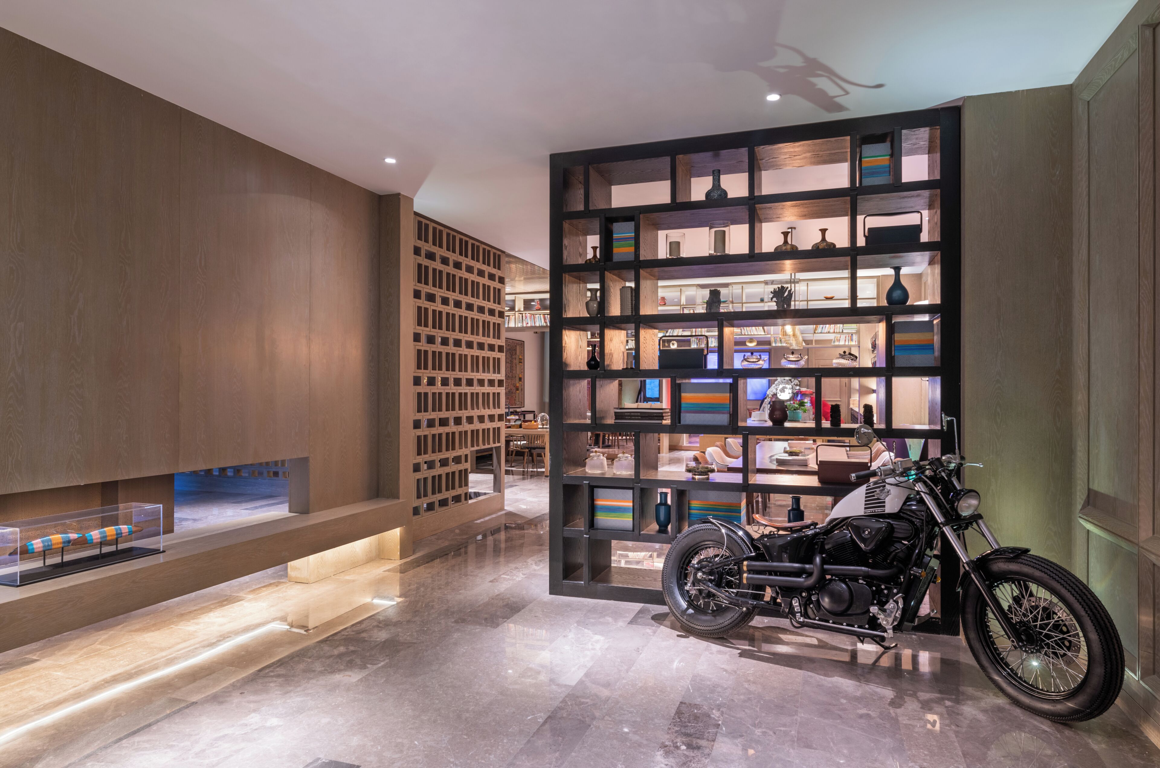 Un intérieur moderne avec une moto, des étagères en bois et une vitrine.