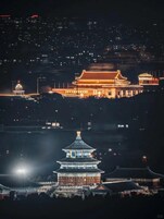 A traditional building with a prominent, illuminated pagoda-like structure at its base, surrounded by a well-lit area.
