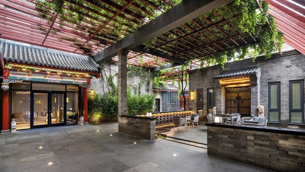 An outdoor patio area with a traditional Chinese architectural style, featuring a tiled roof, stone walls, and a seating area with tables and chairs. - Manxin Mansion Beijing Shichahai Park Nanluoguxiang (Beijing)