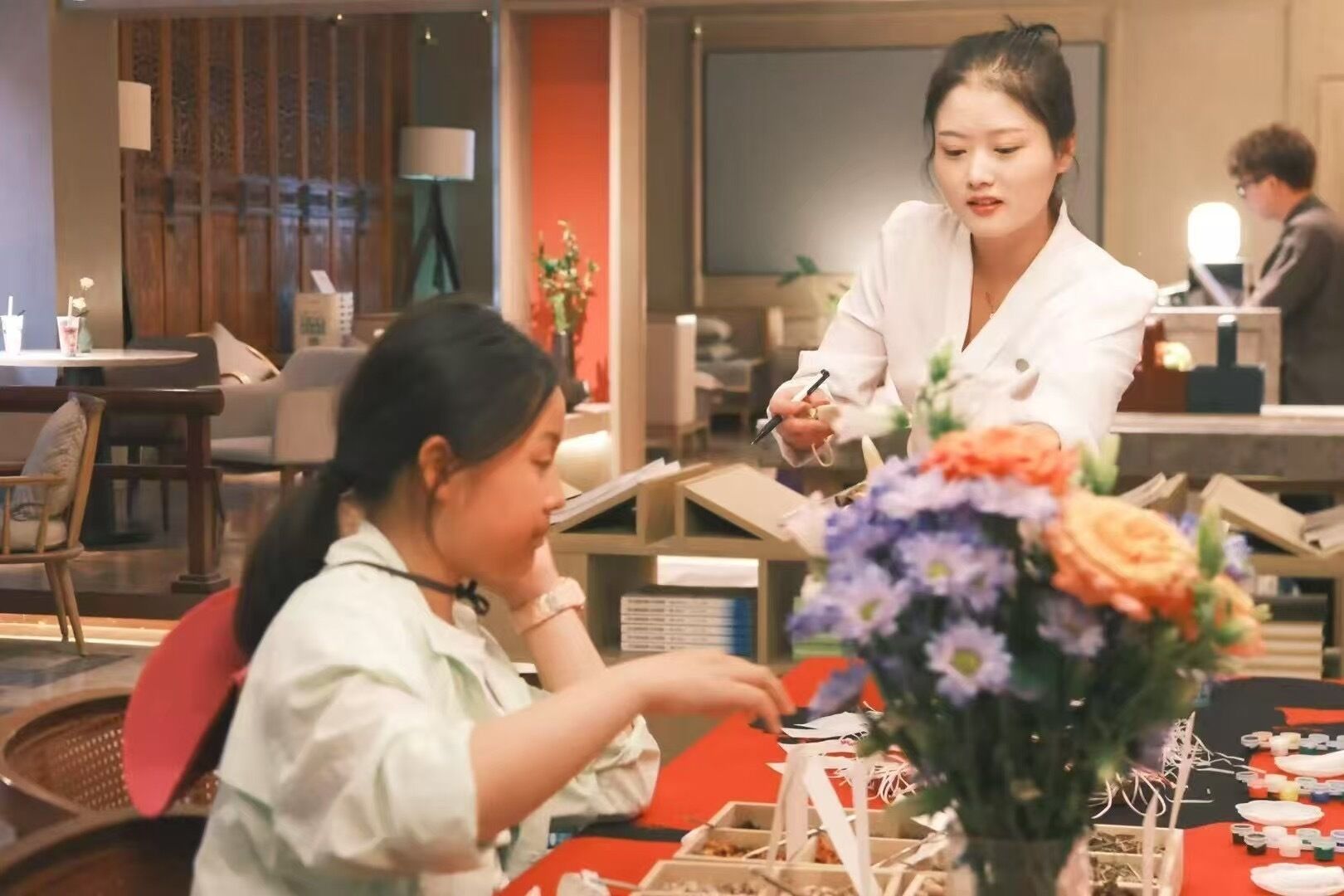 Un espace repas avec des tables, des chaises et un vase de fleurs.