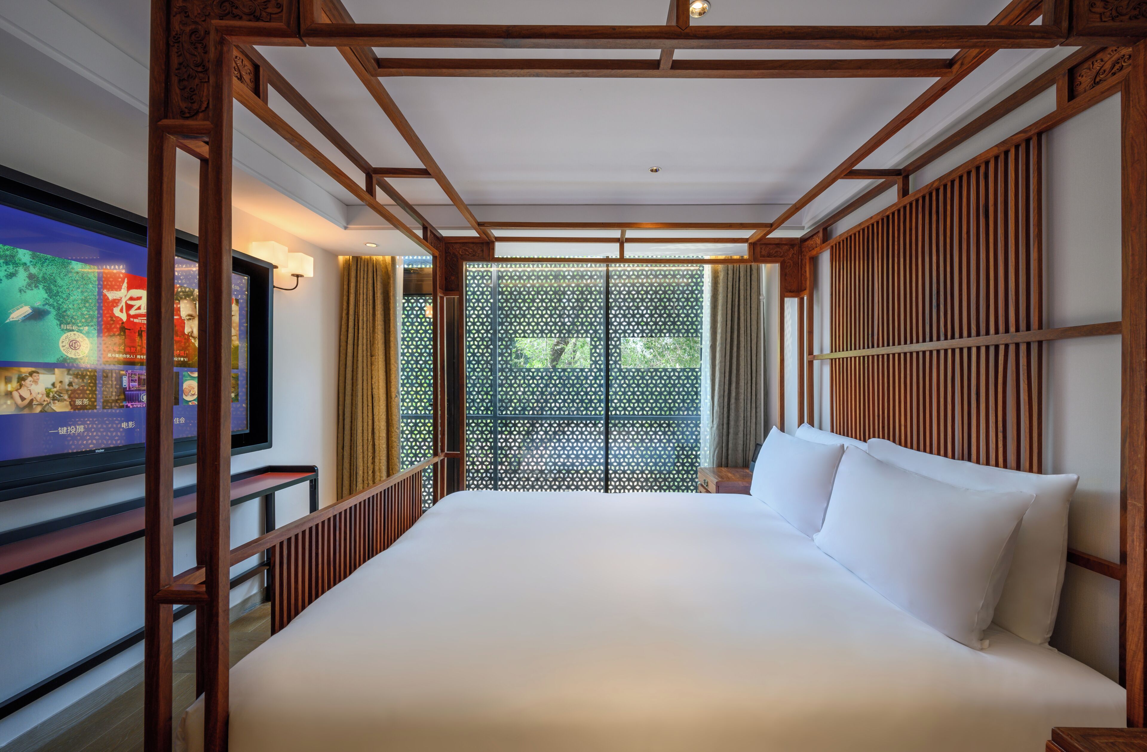 Een hotelkamer met een groot bed, houten hoofdeinde en een televisie links aan de muur.
