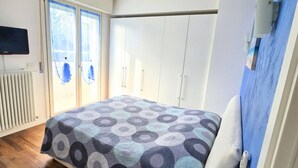 Quarto com cama, televisão, radiador e guarda-roupa.