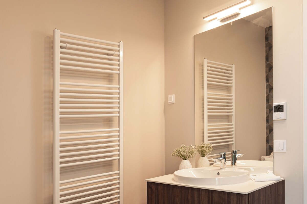 A modern bathroom with a freestanding bathtub, a vanity with a mirror, and a towel rack.