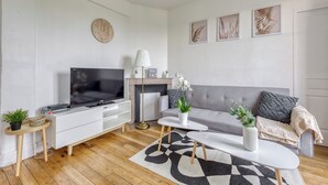 Ein modernes Wohnzimmer mit Flachbildfernseher, einer Couch, einem Couchtisch und einem Kamin.