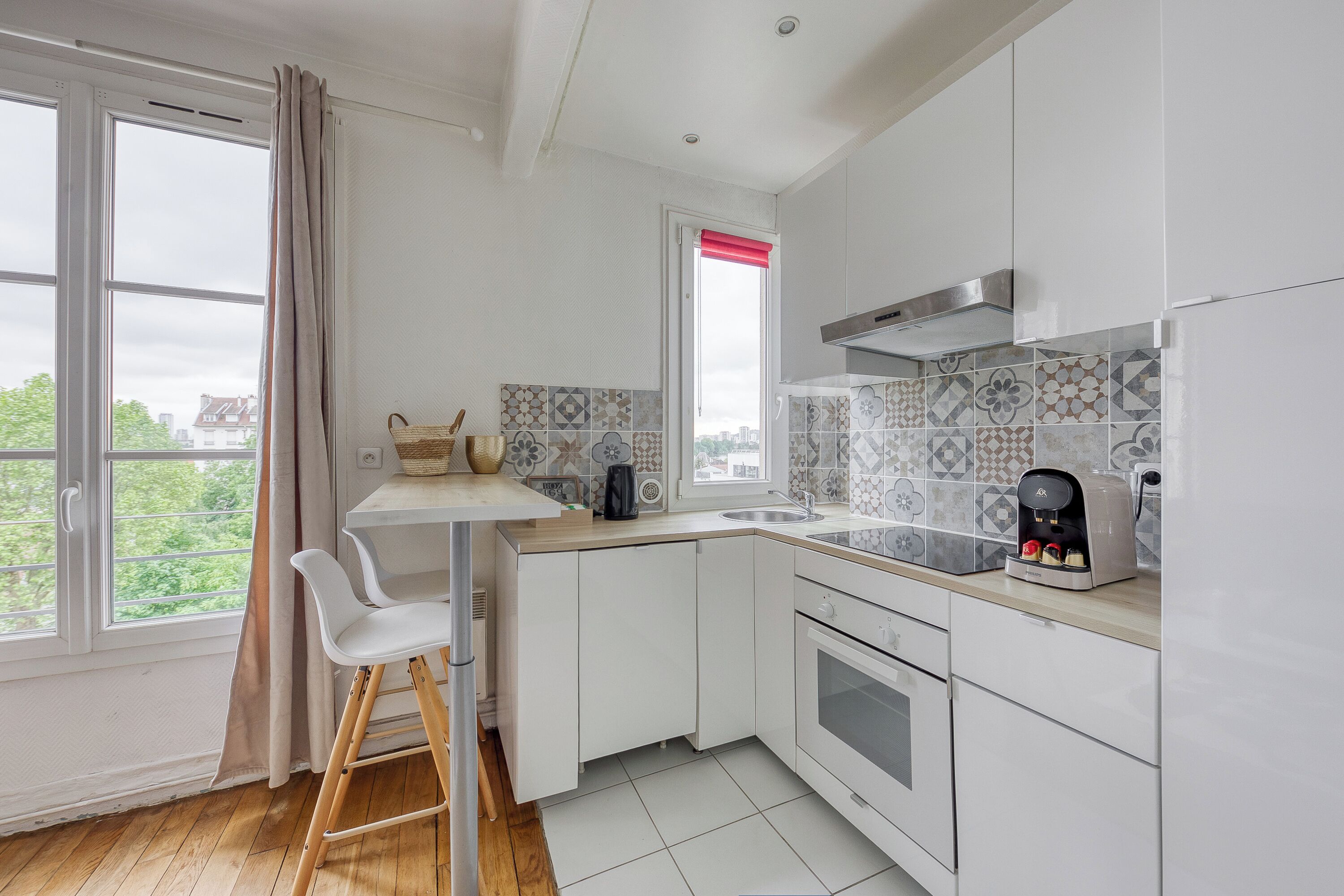 A modern kitchen with white cabinets, a wooden countertop, a built-in oven, and a window with a red blind.