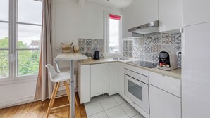 Eine moderne Küche mit weißen Schränken, einer Holzarbeitsplatte, einem eingebauten Backofen und einem Fenster mit rotem Rollo.