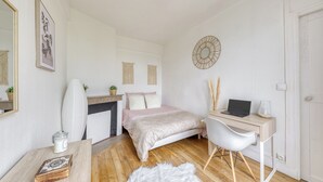 Ein Schlafzimmer mit Bett, Schreibtisch, Stuhl, Spiegel und Kamin.