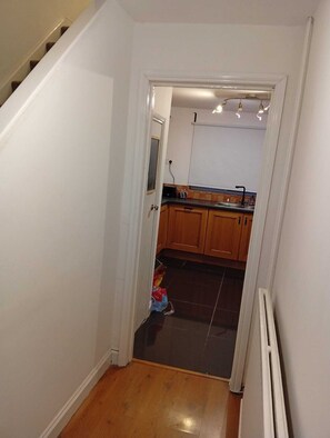 A narrow hallway with a staircase on one side and a kitchen area on the other. - The Linwood Terrace (Eastwood)