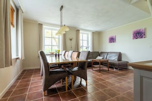 A dining area with a long table, chairs, and a sofa.