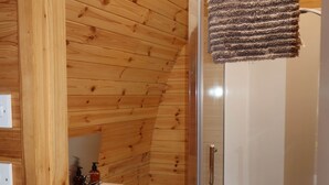 A wooden-paneled bathroom with a glass-enclosed shower, a white sink, and a toilet. - Accessibile Craigengillan Cabin (Dalmellington)