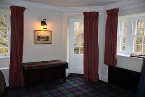 Ein Zimmer mit einer Bank, einem Heizkörper und einem Vorhangfenster.