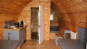 Ein gemütliches, hölzernes Blockhaus mit einer Küchenzeile, einem Bett und einem kleinen Tisch.