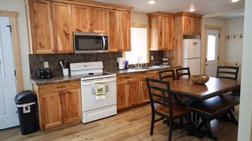 Une cuisine avec des meubles en bois, un four à micro-ondes, une cuisinière, un évier et une table à manger avec des chaises.