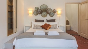 A neatly made bed with pillows, a bedside table, a wall-mounted decorative piece, and a closet. - Apartments Florence - Mezzo Boutique Vista (Firenze)
