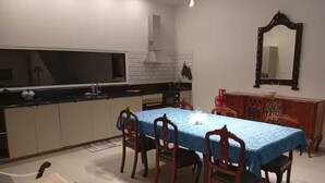 A dining area with a table covered in a blue tablecloth, surrounded by wooden chairs. - Casas do Pargo - Oak Tree House (Lombada Velha)