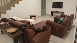 A living room with a staircase, a sofa set, a television, and a small table. - Casas do Pargo - Oak Tree House (Lombada Velha)