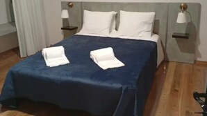 A hotel room with a bed, two bedside tables, and a wooden floor. - Casas do Pargo - Oak Tree House (Lombada Velha)
