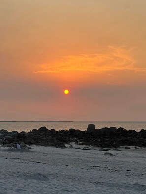 Ein Sonnenuntergang über einer felsigen Küste mit ruhigem Wasser.