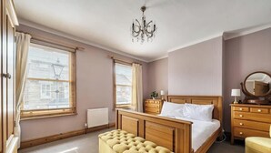 Un dormitorio con una cama de madera, una mesita de noche, un espejo y una ventana con cortinas.