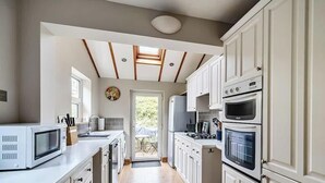 Una cocina compacta con gabinetes blancos, microondas, estufa y lavamanos.