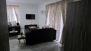 Uma sala de estar com sofá, mesa de centro, televisão e aparador.