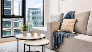 A modern living room with a sofa, a small round table, and a potted plant. - BNBIFY Stylish Melbourne CBD 2BR Apartment | Pool, Spa, Gym (Melbourne)