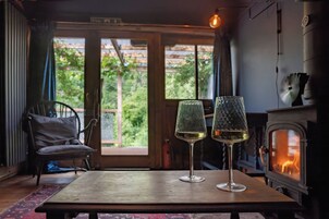 Una habitación acogedora con chimenea, dos copas de vino sobre una mesa y una silla.