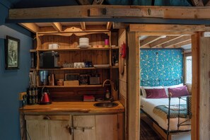 Eine kleine Küche mit Holzschränken, einem Spülbecken und diversen Küchengeräten.