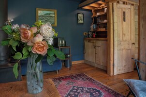 Una habitación con un armario de madera, un jarrón con flores y una alfombra en el suelo.
