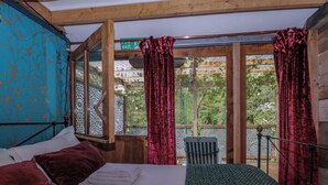 Una habitación con una cama, una ventana con cortinas y vistas a zonas verdes, además de un techo de madera.