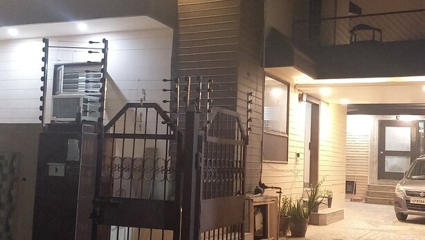 Zona residencial cerrada de noche con un coche estacionado y la entrada a un edificio.