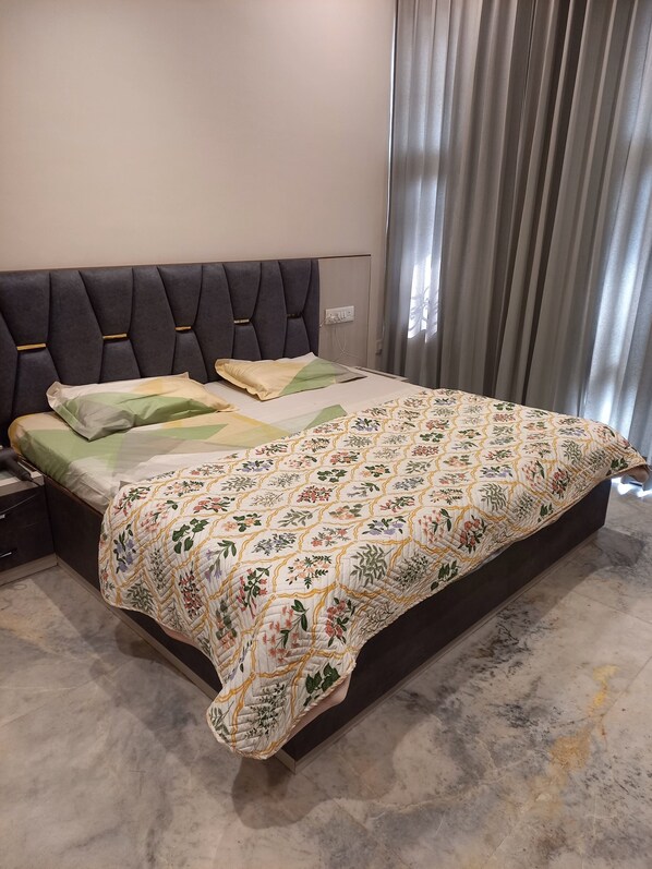 A bed with a floral quilt, a headboard, and a nightstand with a drawer.