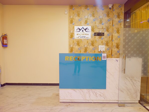 A reception desk with a 'RECEPTION' sign, a hotel logo, and a check-out time sign. - Hotel Shree Raghunandan Palace (Ujjain)