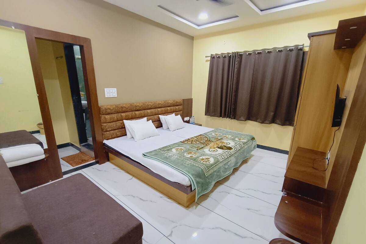 A hotel room with a bed, a desk, a bathroom, and a wardrobe.