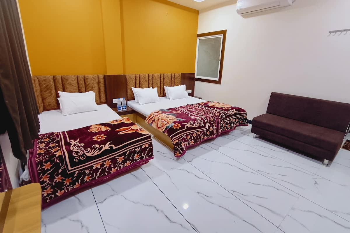 A hotel room with two beds, a sofa, and an air conditioning unit.