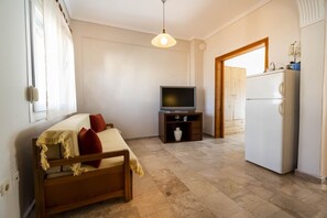 A small, well-lit room with a bed, a TV, and a refrigerator. - Erato Apartment 2 by RentalsPro - Nea Plagia (Plagia)