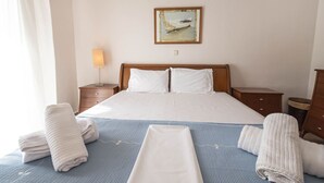 Ein Hotelzimmer mit einem Bett, zwei Nachttischen, einer Lampe, einem Gemälde und Handtüchern.