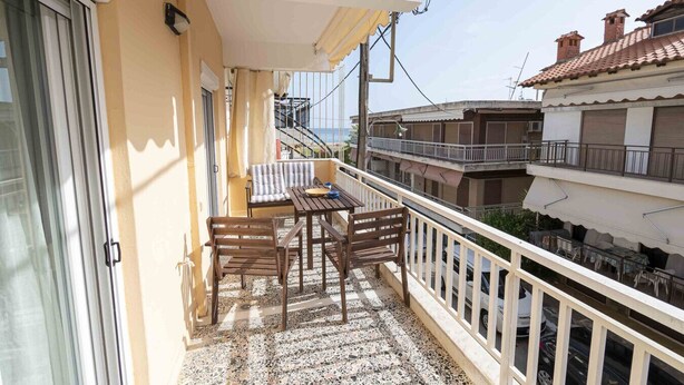 Ein Balkon mit Tisch und Stühlen, einer Brüstung und Blick auf benachbarte Gebäude.