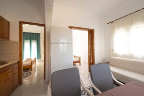 Ein gemütlicher Raum mit Küchenzeile, Essbereich, Sofa und Bett.