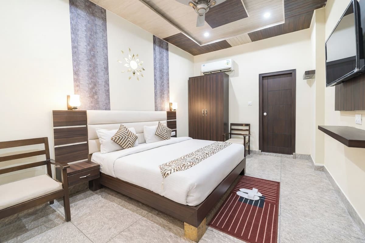 Un dormitorio con cama, mesitas de noche, armario, aire acondicionado, televisor y ventilador de techo.