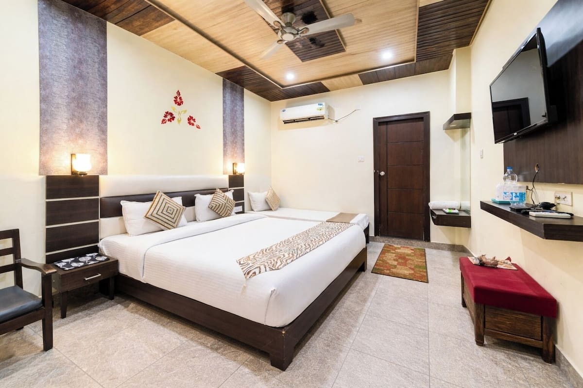 Un dormitorio con cama, mesitas de noche, televisión, espejo y puerta.