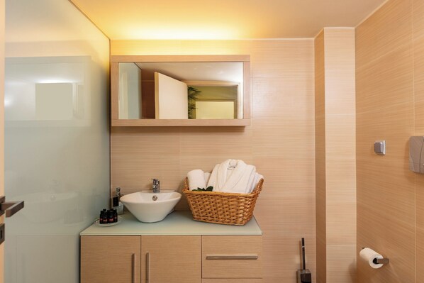 A bathroom with a sink, mirror, and a wicker basket with towels. - Villa Idylle Crete (Rethymno)