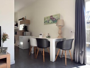 A modern kitchen with white appliances, a dining table with black chairs, and a lamp. - Natuurhuisje Abcoude - Groen Verblijf Buitenhuis (Abcoude)