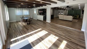 Uma sala ampla com mesa de jantar, sofá e cozinha.