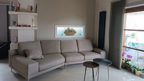 A modern living room with a sofa, a small table, and a potted plant. - YOUR HOUSE (Olbia)