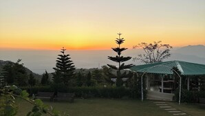 Un espacio verde con un pabellón, árboles y una vista distante de montañas.