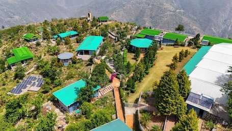A cluster of buildings with green roofs, solar panels, and a central pathway.. Anandam Heights
